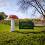 Eingangsbereich des Vereins Gartenfreunde Heddesheim e.V. mit Vereinsschild und großer Fliegenpilzskulptur als markantem Blickfang.